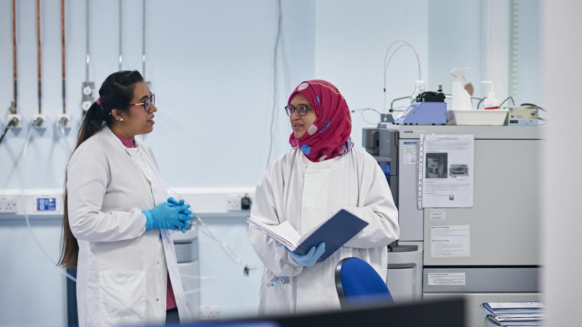 A research technical professional and a student in lab coats talking in a Mass Spectrometry facility