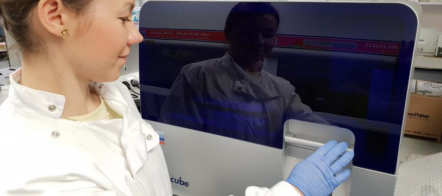 A picture of a technician using a Qiagen QiaCube automated nucleic acid extraction platform